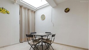 A dining area with a round table and four chairs, a decorative wall hanging, and a skylight. - 2200 Al Castello Home Holidays - Bilo by Barbarhouse (Otranto)