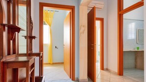 A hallway with wooden doors, a tiled floor, and a visible bathroom with a shower.