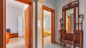 A hotel room with a bed, a nightstand, a mirror, and a door leading to another room.