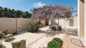 A patio with a table and chairs, a small tree, and a stone wall.