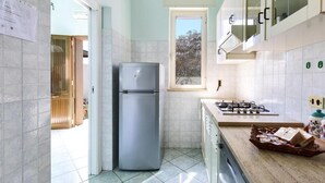 A compact kitchen with a refrigerator, stove, and a window.
