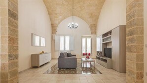 A spacious living area with a high arched ceiling, a grey sofa, a coffee table, and a TV. - 2321 Dimora Terra Barone by Barbarhouse (Presicce-Acquarica)