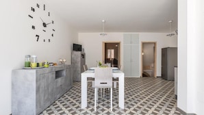 A modern kitchen with a dining area, featuring a clock, a built-in fridge, and a patterned floor. - 2321 Dimora Terra Barone by Barbarhouse (Presicce-Acquarica)