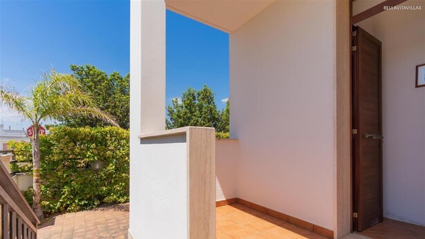 A balcony with a tiled floor, a door, and a view of greenery and a stop sign. - 2406 Villa Cieloazzurro - Mono B by Barbarhouse (Nardò)
