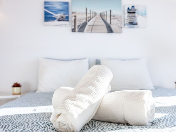 A neatly made bed with white linens and a patterned bedspread.