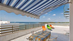 A terrace with a view of the sea, a table with chairs, and colorful chairs. - 1132 Attico Isola dei Conigli (Porto Cesareo)