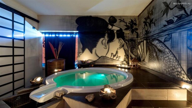 A spa area with a hot tub, decorative stones, and a mural on the wall. - 1745 Silver Hotel - Matrimoniale (Matino)