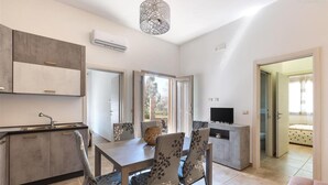 A modern kitchen with a dining area, a TV, and a sofa. - 2300 Villino Vanessa (Porto Cesareo)