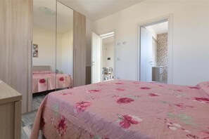 A bedroom with a bed, a wardrobe, and a bathroom visible through an open door. - 2092 Villa Il Fenicottero Salentino (Manduria)