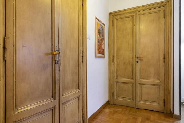 A hallway with two wooden double doors, a framed picture on the wall, and a wooden floor. - Walking distance for tourism, shopping and business. Do as Romans do (Rome)