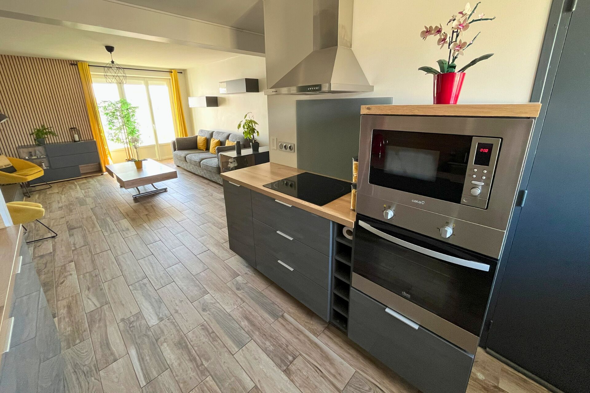 Eine moderne Küche mit Einbauofen, Mikrowelle und einer Holzausziehtischplatte.