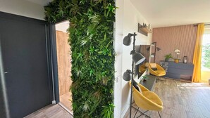 A modern interior with a vertical garden, a yellow chair, and a desk with a lamp.