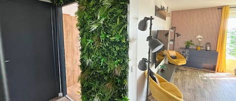 Un interior moderno con un jardín vertical, una silla amarilla y un escritorio con una lámpara.