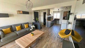 A modern living room with a grey sofa, yellow cushions, a wooden coffee table, and a hanging chair.