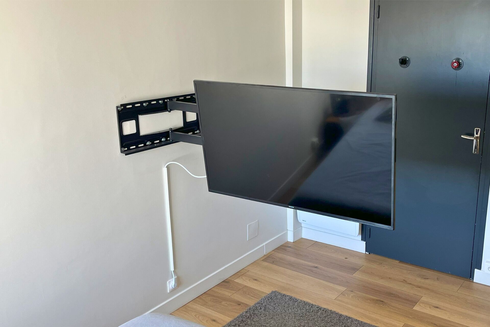 A flat-screen TV mounted on a wall with a cable running to it.