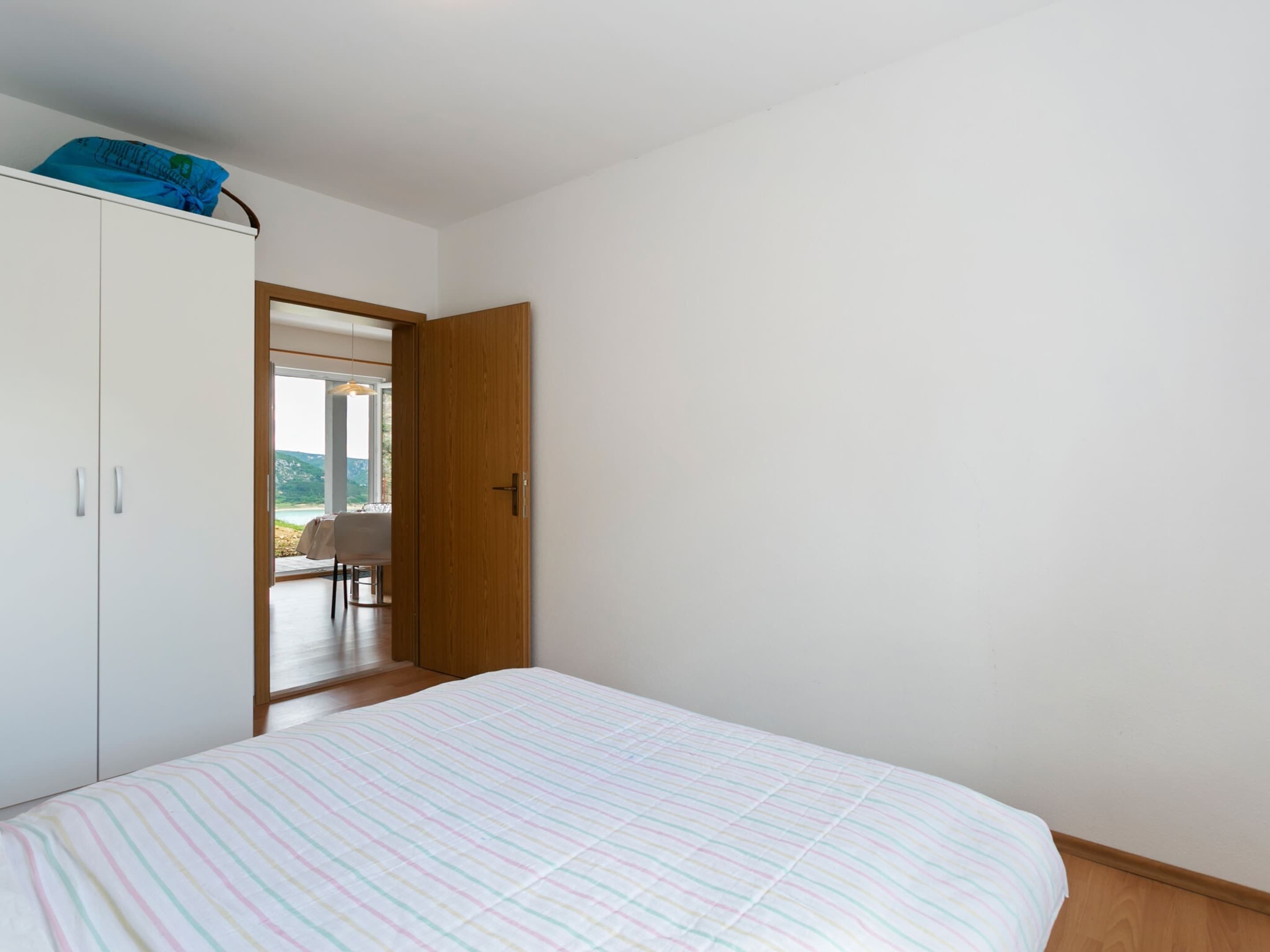 A bedroom with a bed, a wardrobe, and a door leading to a balcony.