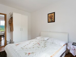 Une chambre à coucher avec un lit, une armoire, un tableau et une table recouverte d’une nappe.