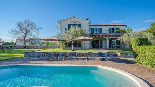 Une grande maison avec une piscine, un espace extérieur aménagé et un jardin bien entretenu.