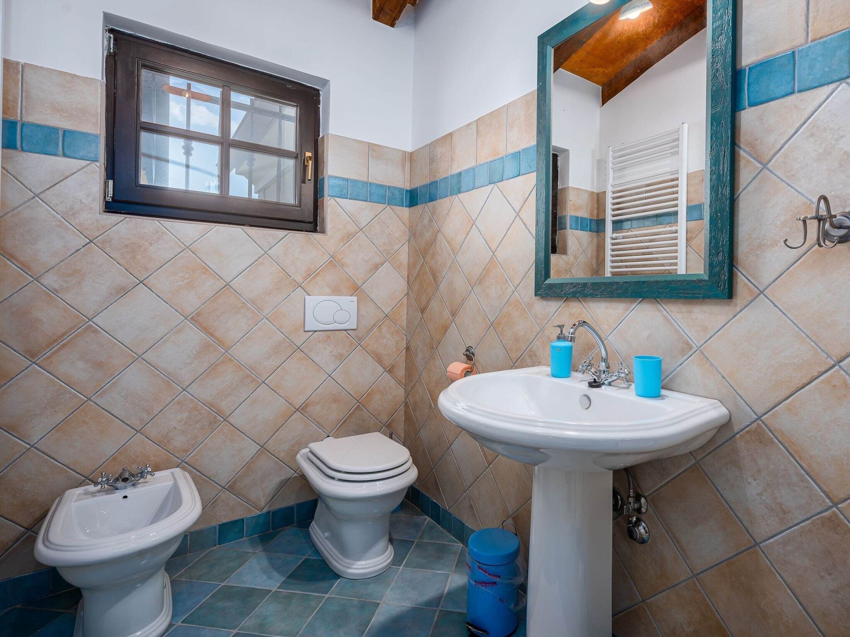 Un baño con inodoro, lavamanos, bidé y ventana.