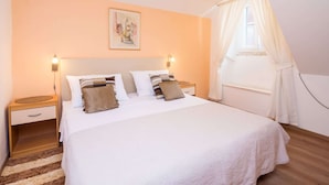 A bedroom with a bed, nightstands, a painting, and a window with curtains. - Apartment Neve - Two Bedroom Apartment (Dubrovnik)