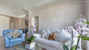 A living room with a white sofa, blue armchair, and glass coffee table. - 2248 Villa Padangi in Gallipoli (Gallipoli)