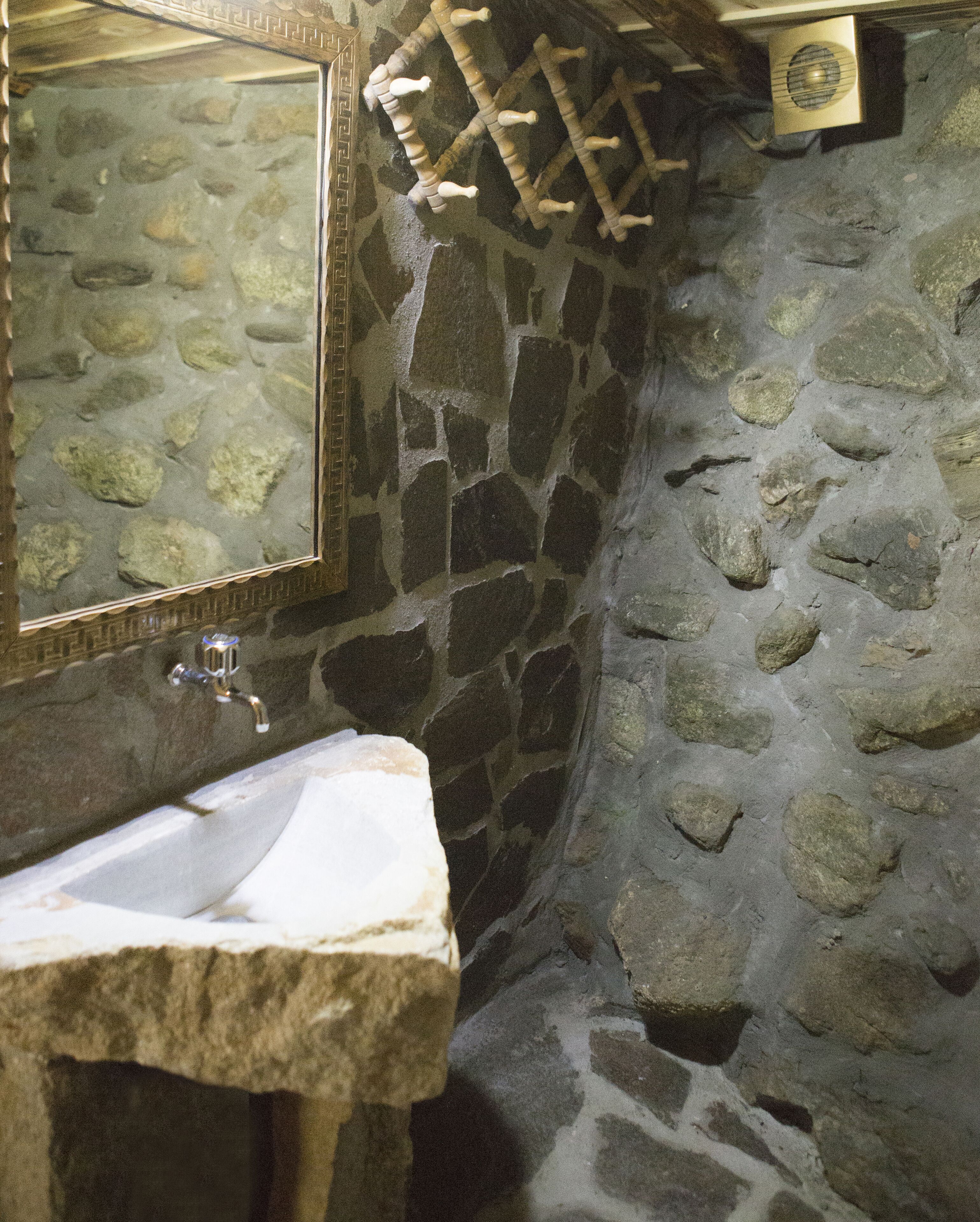 Un bany de pedra amb un lavabo i un mirall.