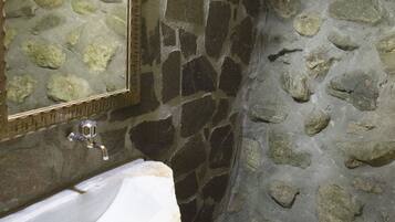 Un bany de pedra amb un lavabo i un mirall.