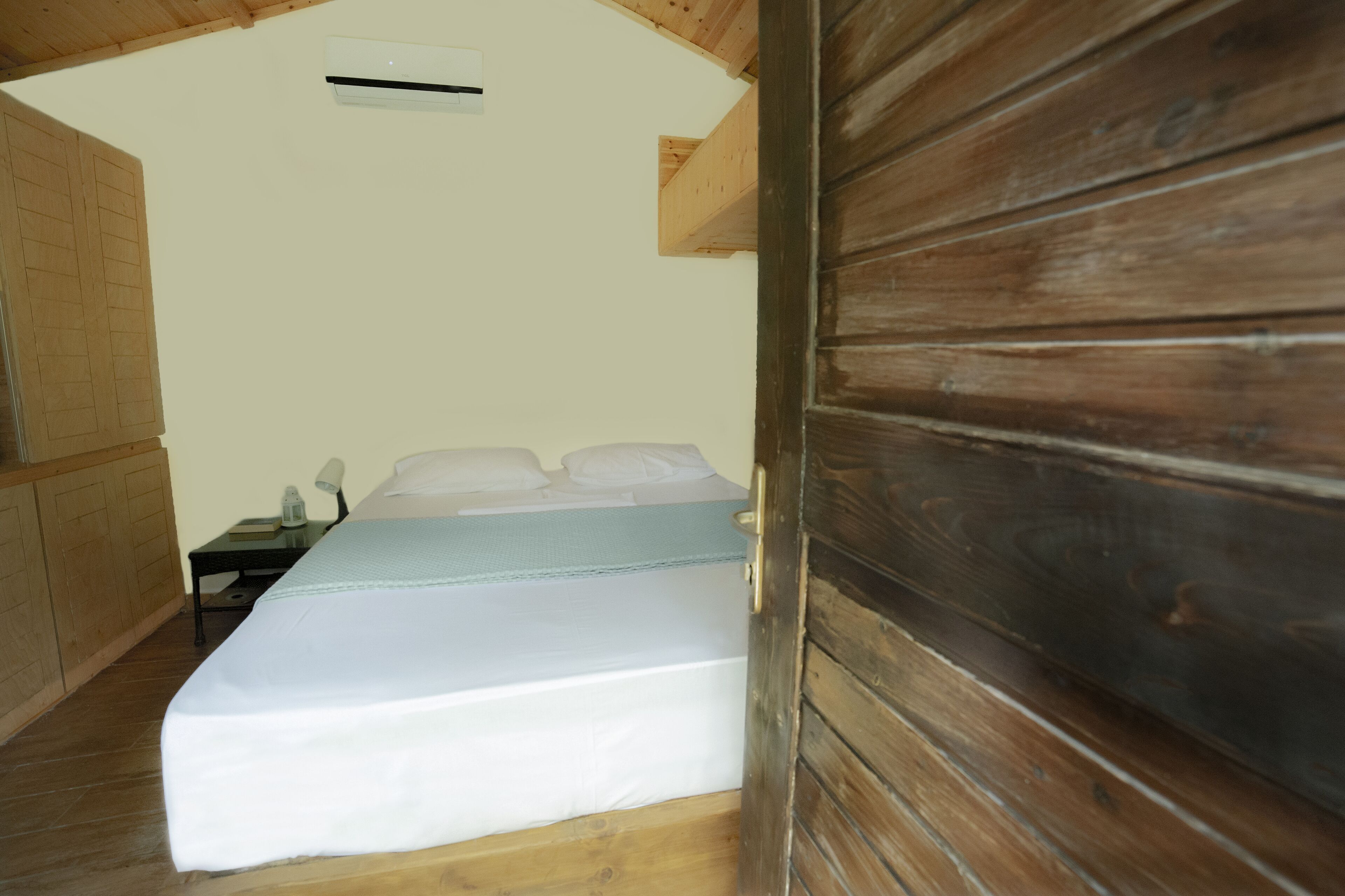 Un dormitorio con una cama, una mesita de noche y un techo de madera.