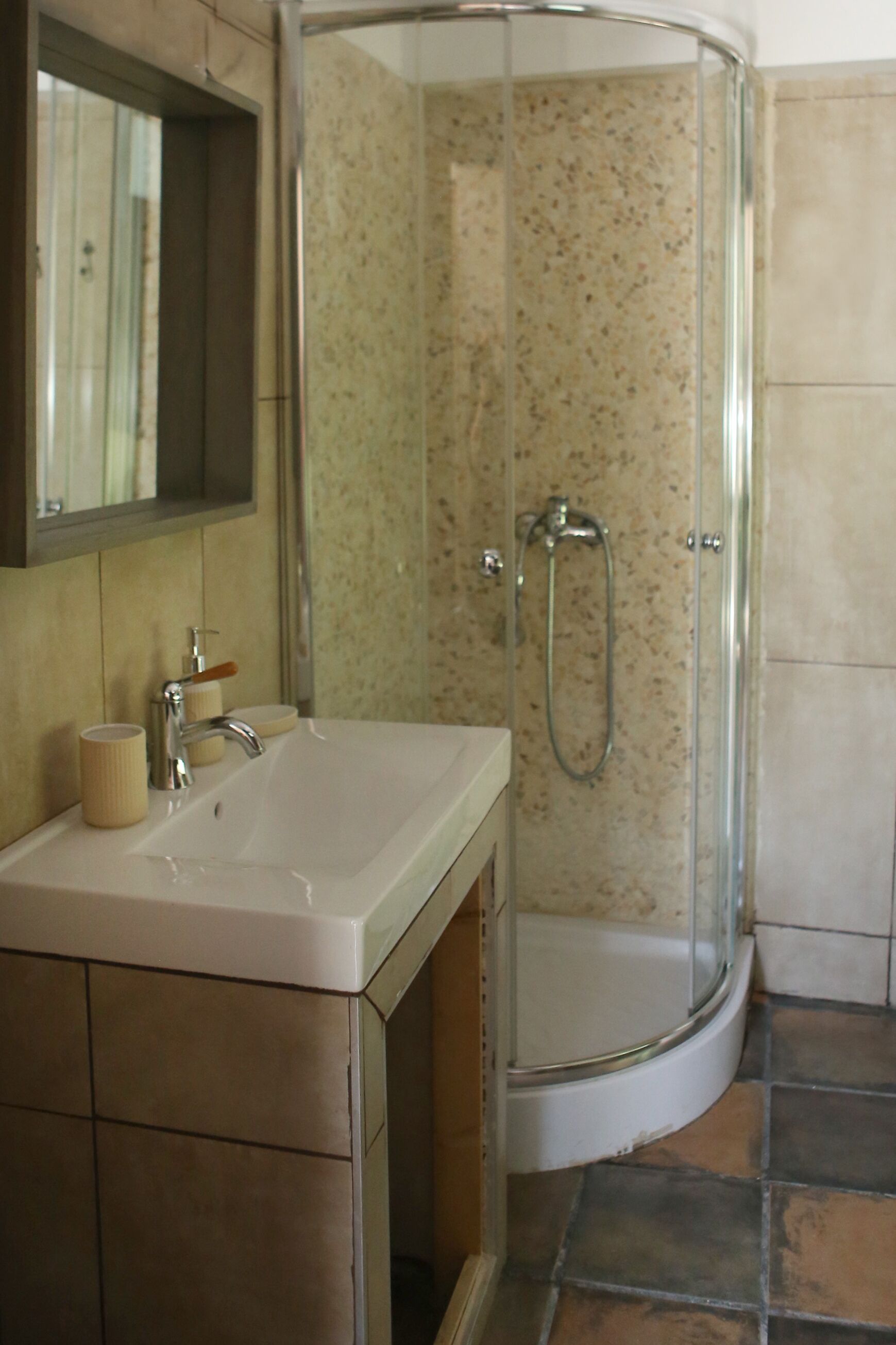 A bathroom with a white sink, a mirror, and a glass-enclosed shower.