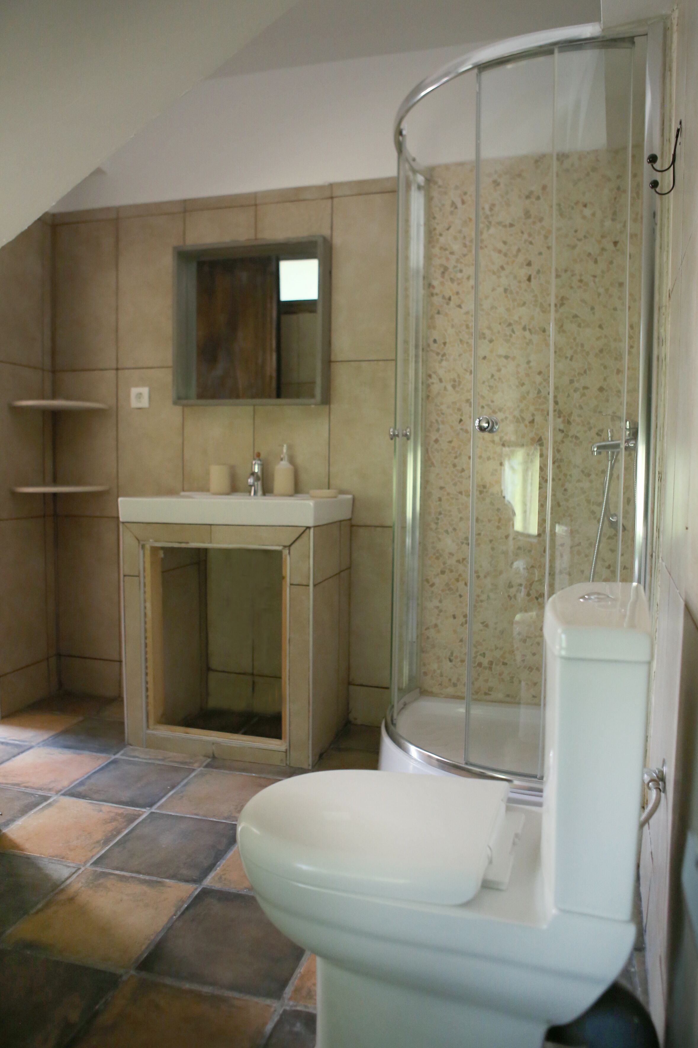 A bathroom with a toilet, a sink, a shower enclosure, and a mirror.