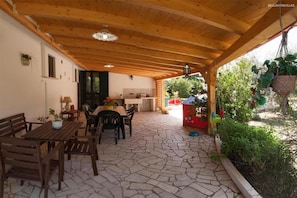 A covered patio with wooden furniture, a tiled floor, and potted plants. - 380 Villa Tipica a Pochi km Dalle Spiagge di Torre San Giovanni (Ugento)