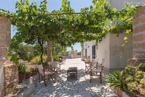 A courtyard with stone flooring, wooden chairs, a table, and a pergola covered with grapevines. - 380 Villa Tipica a Pochi km Dalle Spiagge di Torre San Giovanni (Ugento)
