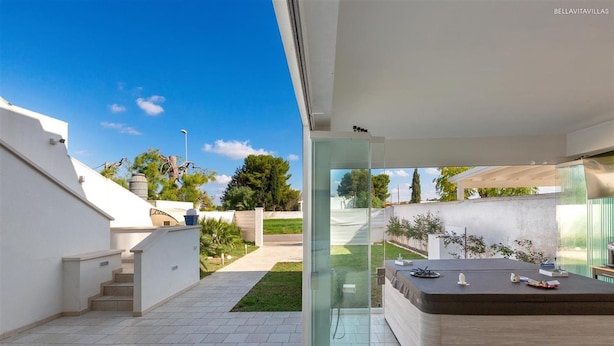 A modern outdoor living area with a glass enclosure, a seating area, and a view of the surrounding landscape. - 1283 B B Dreams and Delights - Sea Sight Camera Familiare (Porto Cesareo)