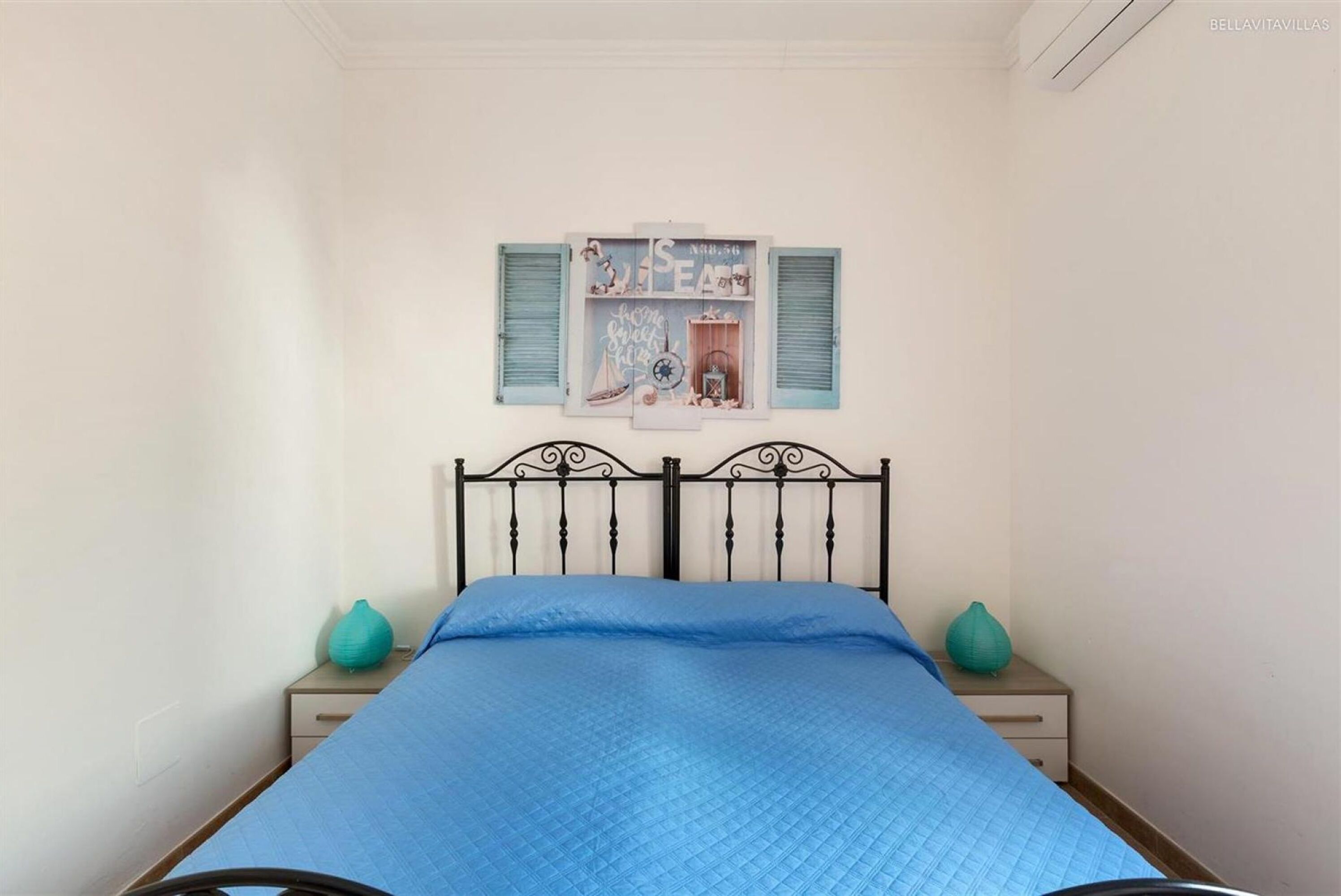 Een slaapkamer met een bed, een nachtkastje en een decoratie aan de muur.