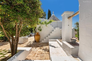Stroll through this serene courtyard, featuring a paved pathway, a unique staircase, and a rustic vase.