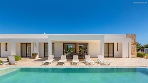 Uma casa moderna com piscina, área de estar externa e um alpendre.
