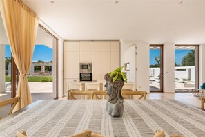 Ein stilvoller Essbereich mit Tisch, Stühlen, einer Blumenvase und einer Küche im Hintergrund.