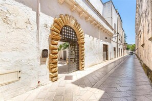 A narrow street with a stone archway leading to a building with a metal gate. - 2043 Antica Dimora Stasi by Barbarhouse (Presicce-Acquarica)