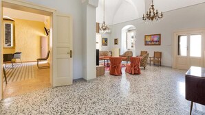 A spacious living area with a high ceiling, a chandelier, and a large window. - 2043 Antica Dimora Stasi by Barbarhouse (Presicce-Acquarica)