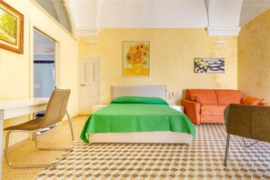 A bedroom with a bed, a desk, two chairs, a sofa, and two paintings on the wall. - 2043 Antica Dimora Stasi by Barbarhouse (Presicce-Acquarica)