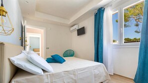 A bedroom with a bed, a TV, and a window with curtains. - 2055 Villa San Teodoro (Avetrana)