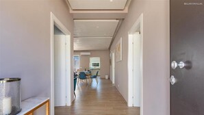 A corridor with a dining area in the background, a door with a lock, and a trash can on a console table. - 2055 Villa San Teodoro (Avetrana)