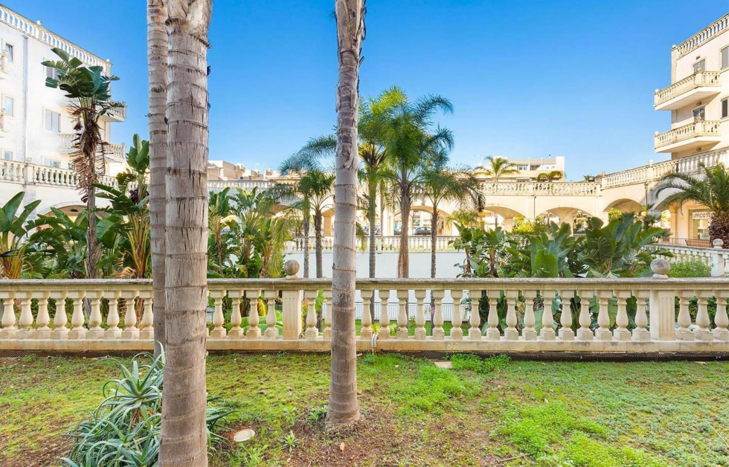 Un patio con palmeras, una fuente y un edificio con balcones.