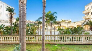 A courtyard with palm trees, a fountain, and a building with balconies. - 2122 Appartamento Corso Italia II by Barbarhouse (Gallipoli)