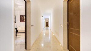 A hallway with a wooden door on the right, a white wall with a framed picture on the left, and a tiled floor. - 2122 Appartamento Corso Italia II by Barbarhouse (Gallipoli)