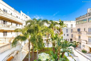 A courtyard with palm trees, a fountain, and multi-story buildings with balconies. - 2122 Appartamento Corso Italia II by Barbarhouse (Gallipoli)
