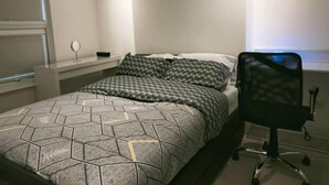 Ein Schlafzimmer mit Bett, Stuhl, Nachttisch und Wandlampe.
