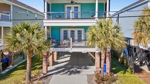 A two-story house with a balcony, a covered front porch, and palm trees. - Surfside Beach Family Retreat w/ Private Pool & 5BRs (Surfside Beach)
