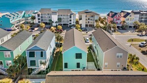 A coastal residential area with colorful houses, a parking lot, and a view of the ocean. - Surfside Beach Family Retreat w/ Private Pool & 5BRs (Surfside Beach)