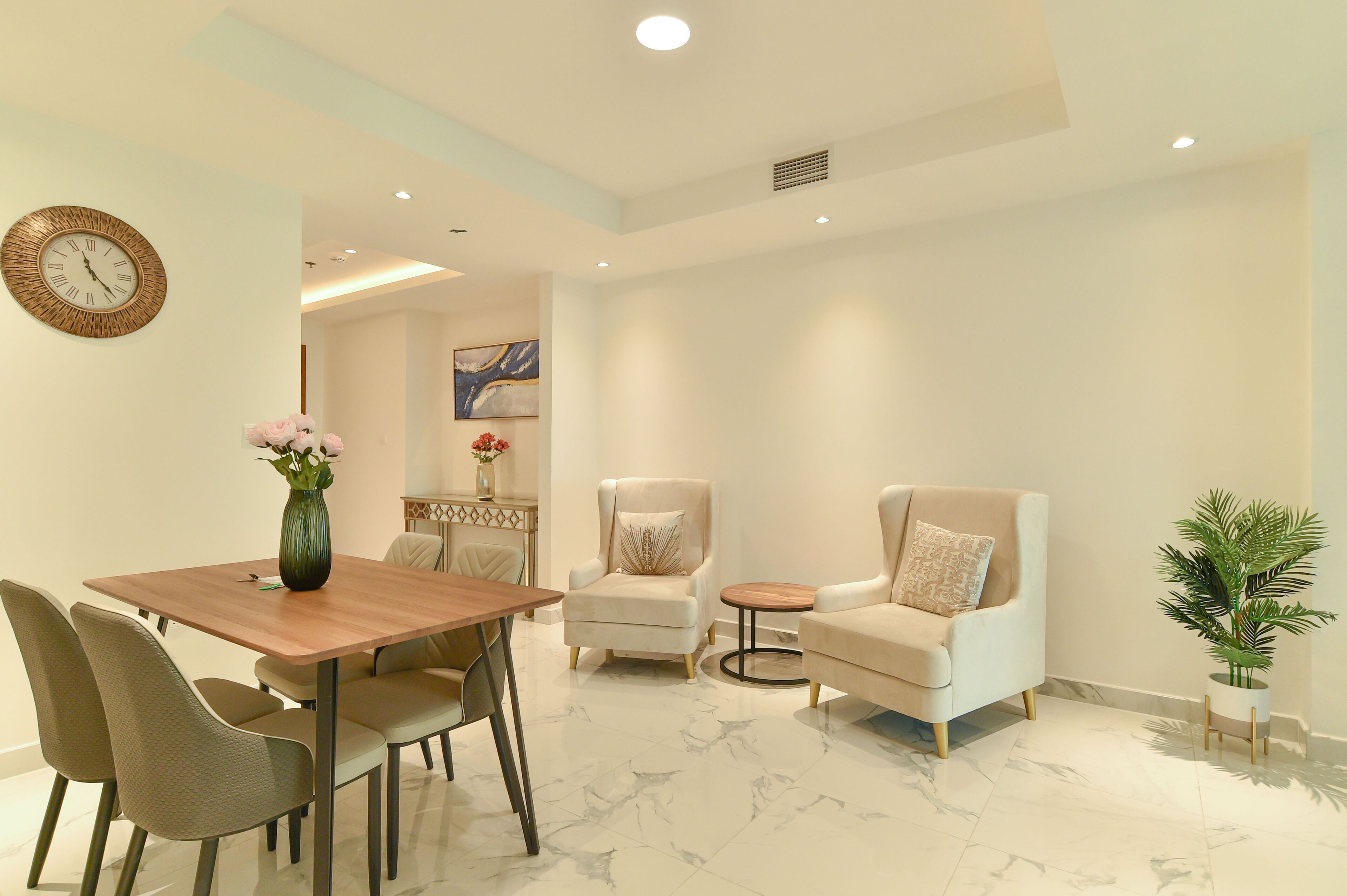 A modern living room with a dining area, featuring a wooden table, comfortable seating, and a decorative plant.
